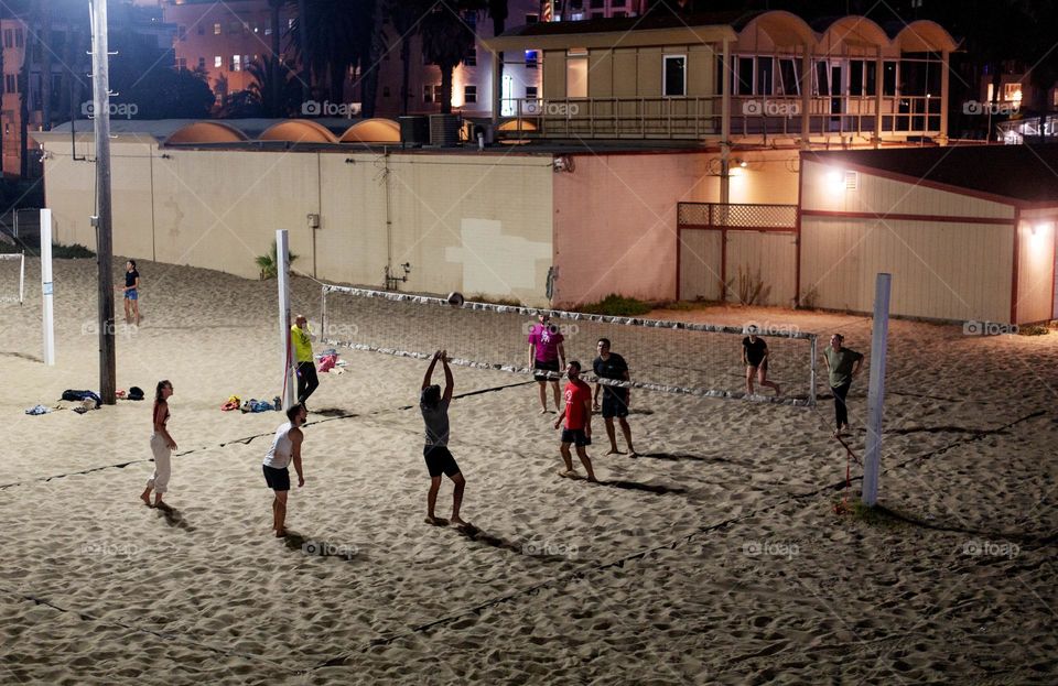 Group of friends playing beach volleyball in the summer 