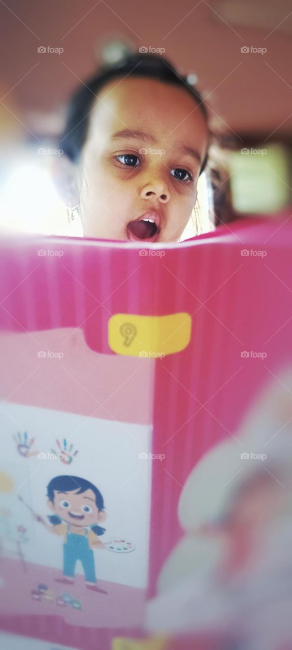 Cute girl reading a kid book very interestingly