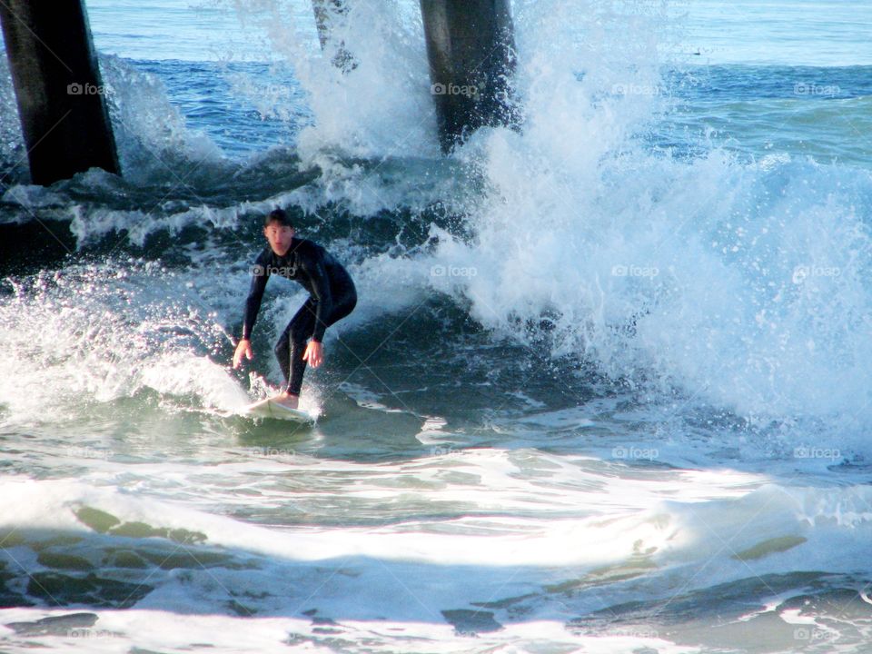 Braving the Pier. Surfer challenging the pier in Huntington Beach, California 