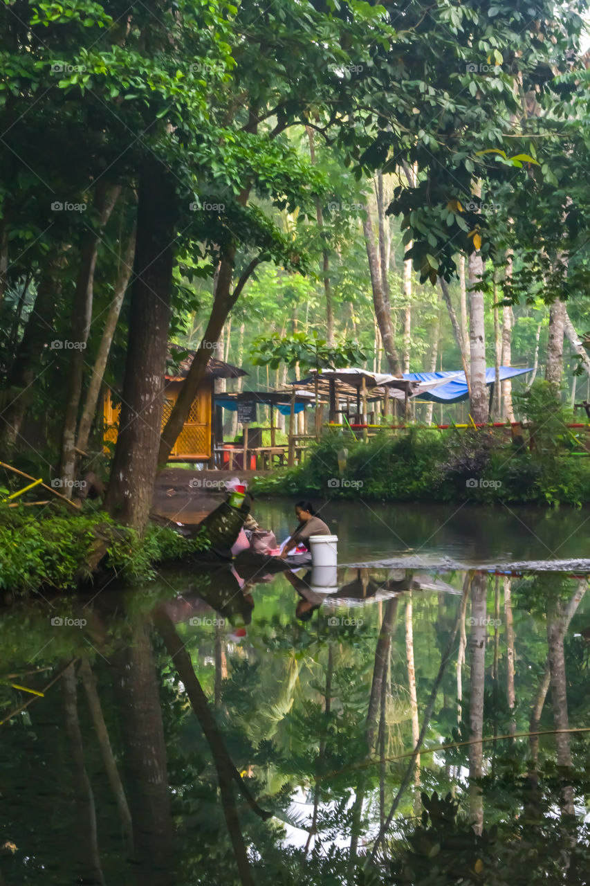 a photo with peace in the river. seen two people washing in the river