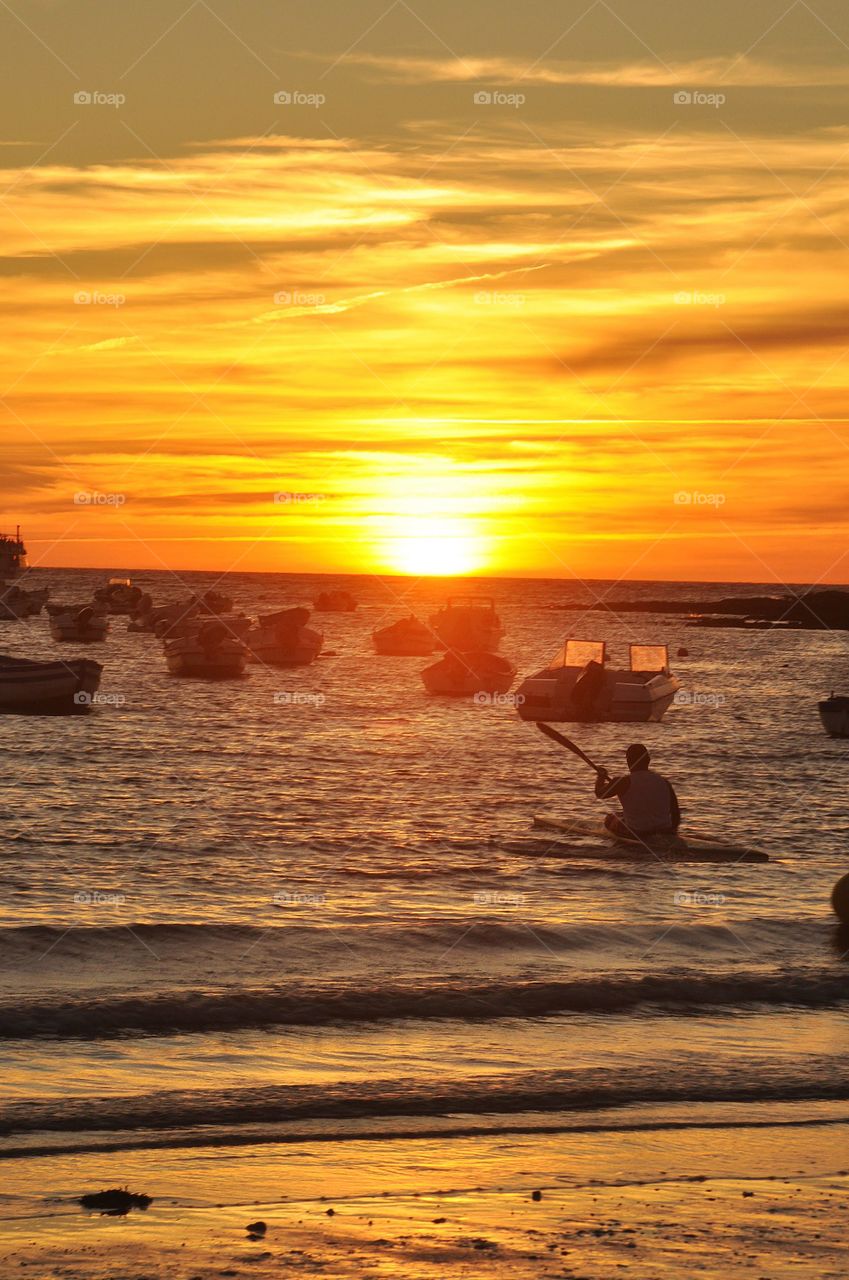 Man rowing into the sunset on a Spanish beach