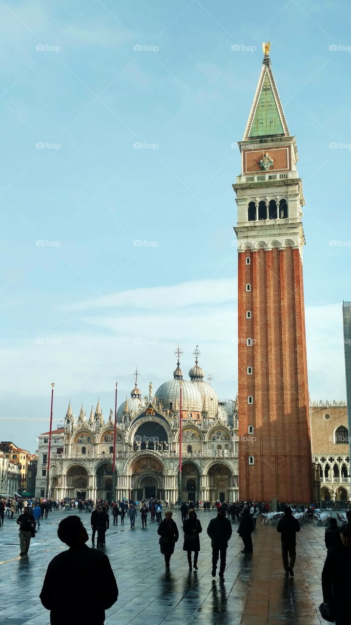 Visitors admire the Basilica and bell tower in Venice's Piazza San Marco