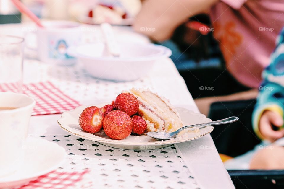 Strawberries and cake on a plate outdoors on a table