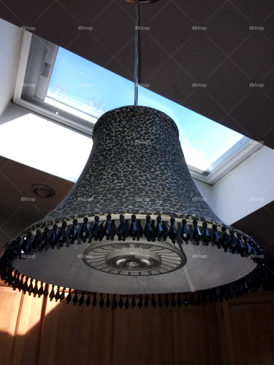 Drop LED spotlight in my kitchen hanging over my oak butcher block. The shade is leopard print with beads hanging, a reflection of me!😊One of the two skylights is visible in this pic, blue sky today.