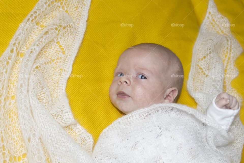 A newborn baby on a yellow and gray background. A photo shoot in the style of Newborn and lifestyle.