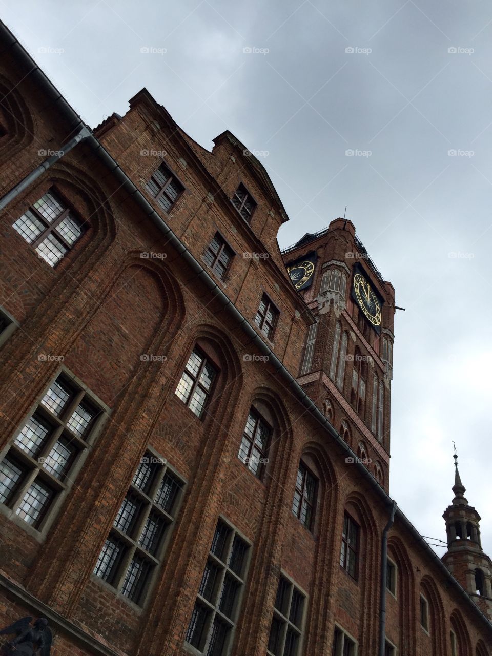 Town city hall with a clock in Torun against cloudy sky