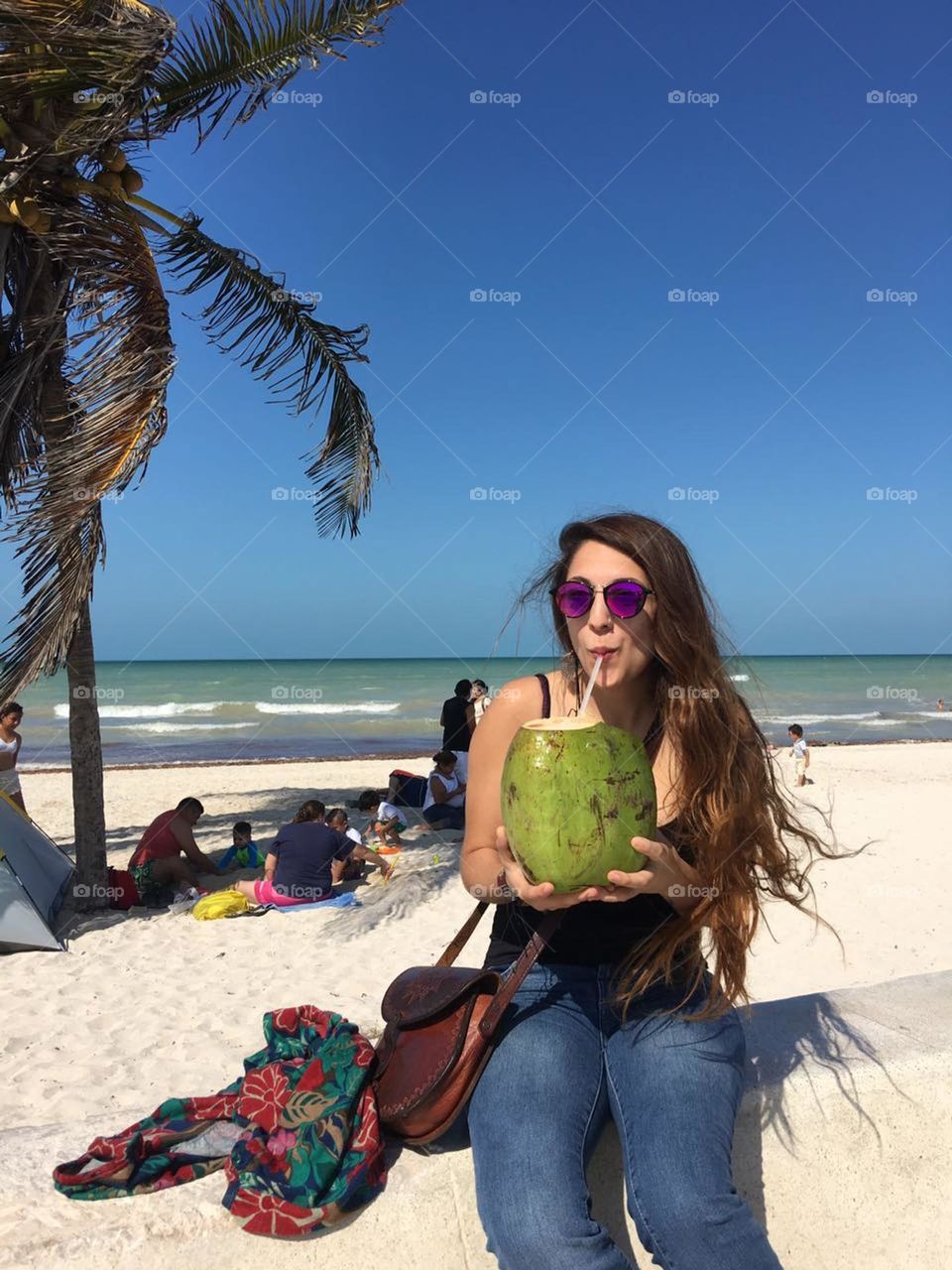 Ella toma agua de coco en una tarde veraniega en la playa