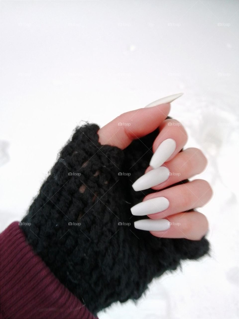 White manicure on long natural mails/ White nails in the winter /Snowy background with fingerless gloves