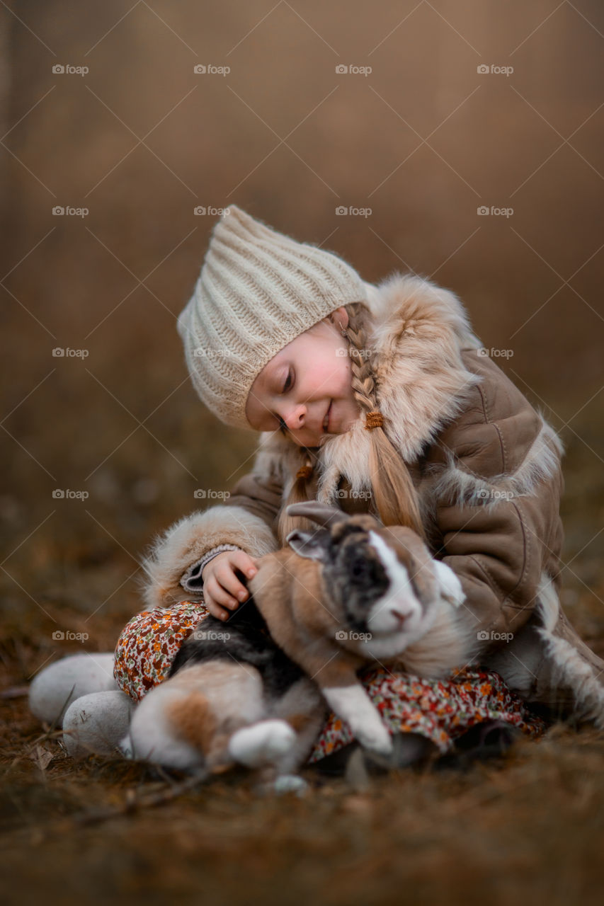 Cute Little girl with bunny in a forest at misty autumn evening 