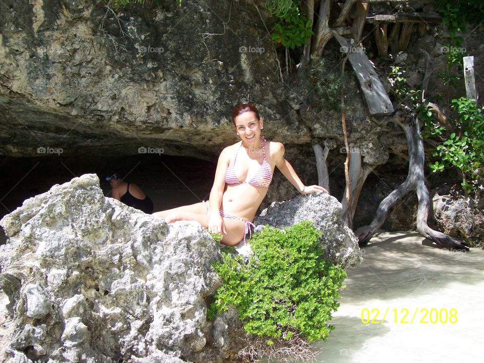 Woman in bikini sitting on rock