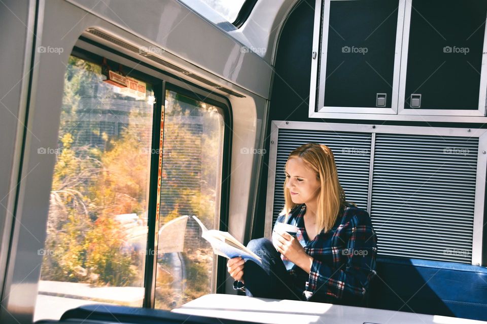 Woman reading book and drinking coffee while taking train acros the usa