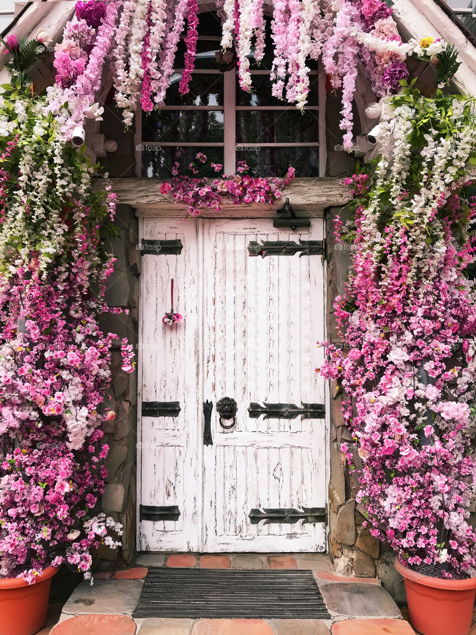 White wooden door decorated by pink flowers 