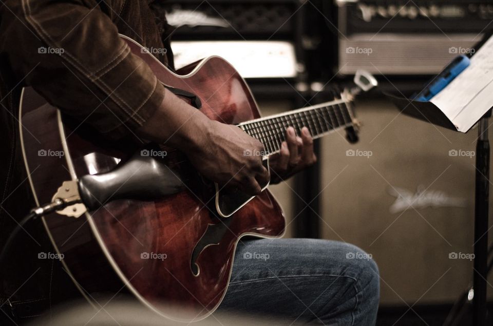 Midsection of man playing with guitar