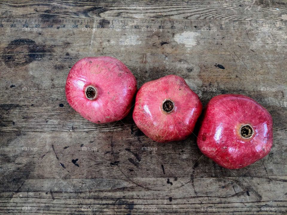 three pomegranates on a wooden table