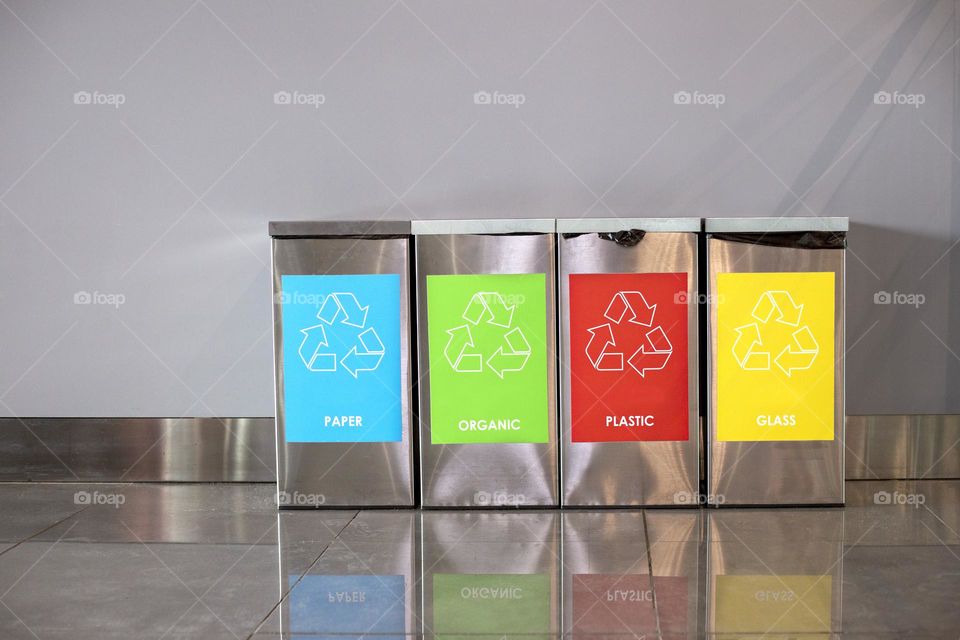 Four metal bins for different garbage - paper, organic, plastic, glass. Sorting rubbish concrete 