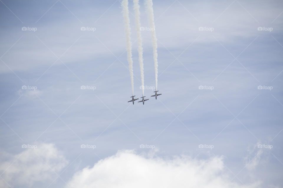 The plane is flying against the blue sky. Aerobatic figure, military aircraft.