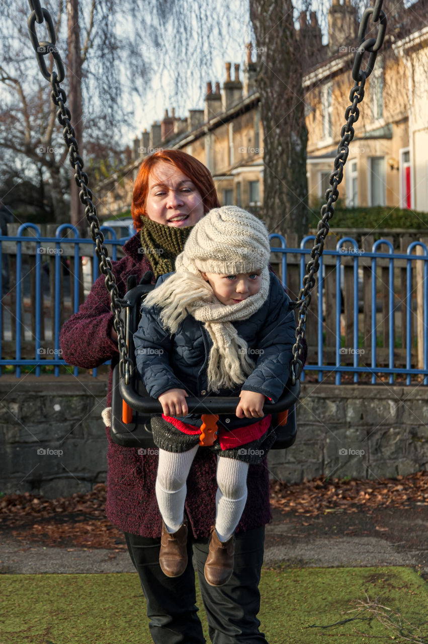 Mother and daughter having fun on swing.