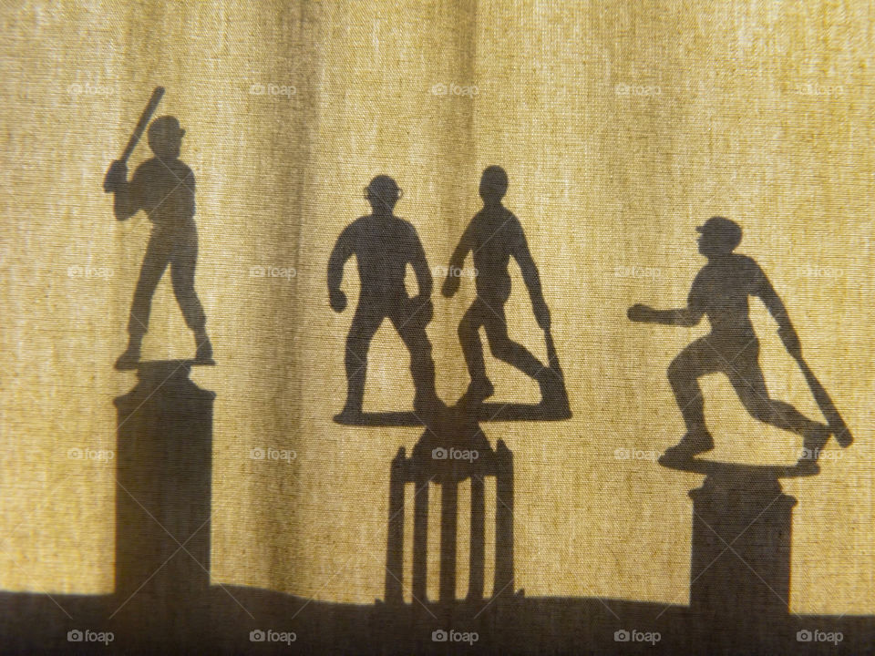 Silhouettes of baseball trophies behind curtains