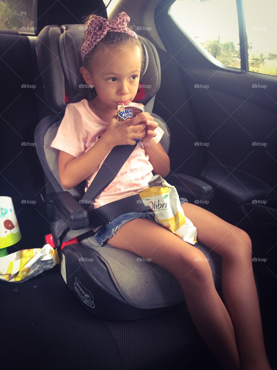 Little girl drinking juice while sitting in car