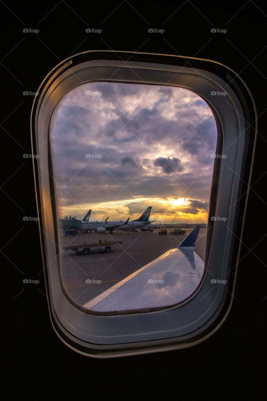 Beautiful dramatic sunset in the distance over the wing of a plane looking out the window. 