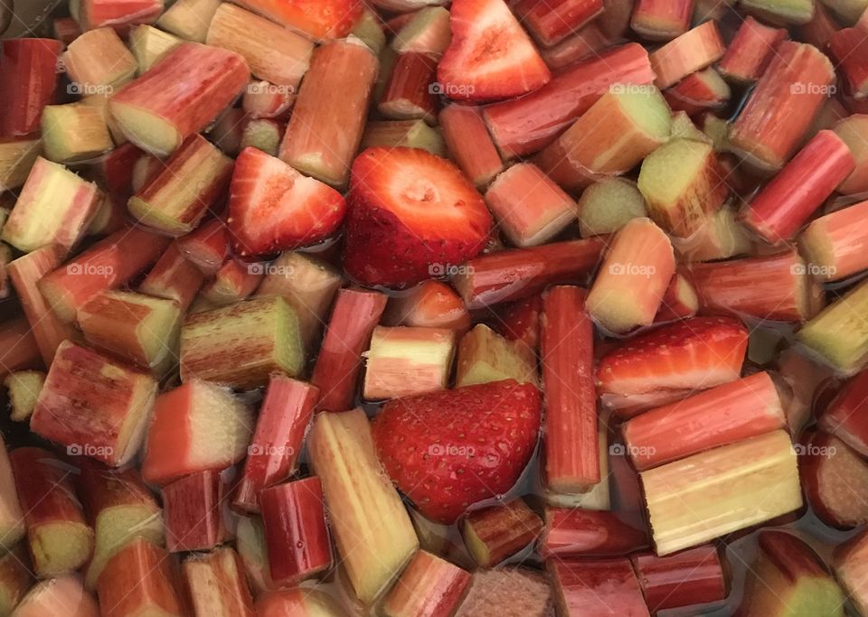 Chopped, red, Strawberries and rhubarb in water and sugar, floating ready to be cooked. A spring treat. 