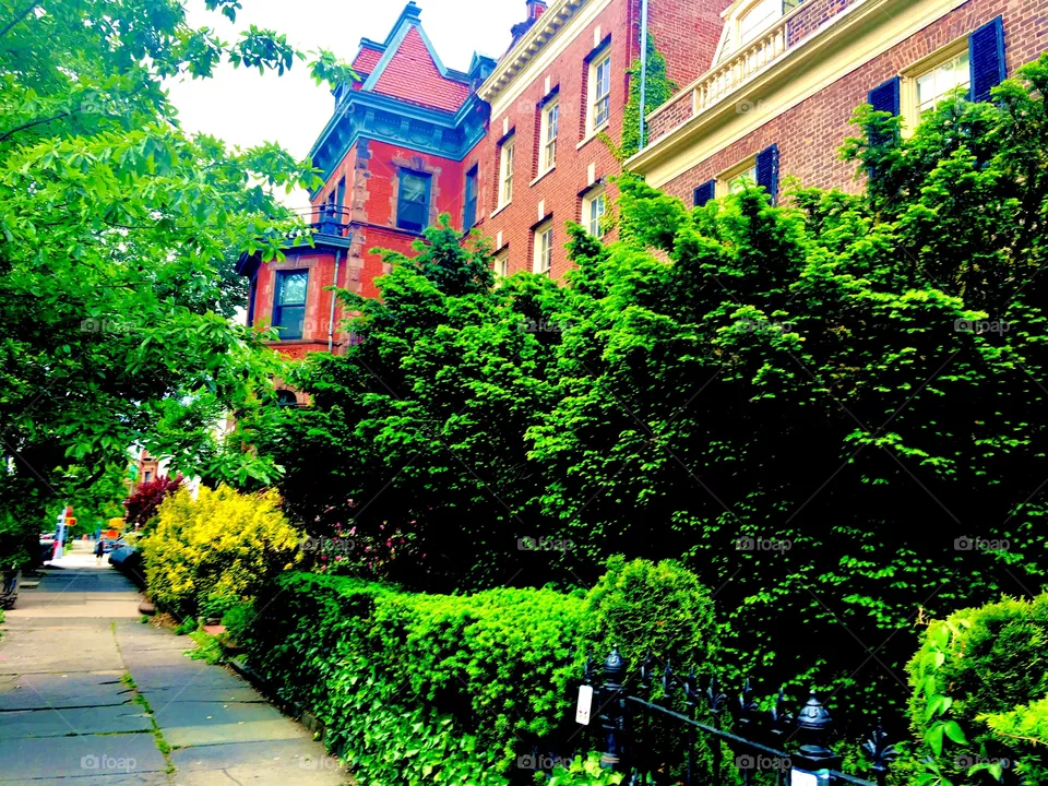 A Forest Gre, Bklyn brownstone around Fulton St with a side tower with colored decorations and a steeple rooftop. Many such buildings are in the area styled as if from a bygone era, 2019. Hypnotic Productions