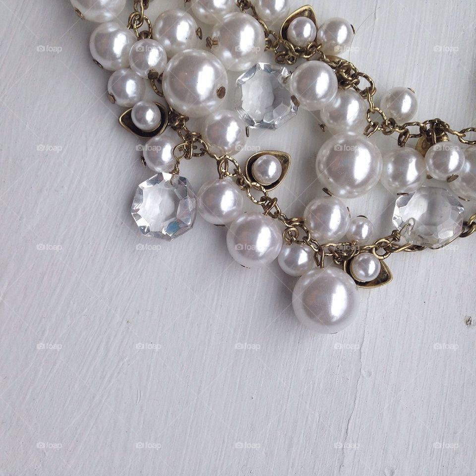 Photo of strands of Pearls and diamonds with gold chain flatlay