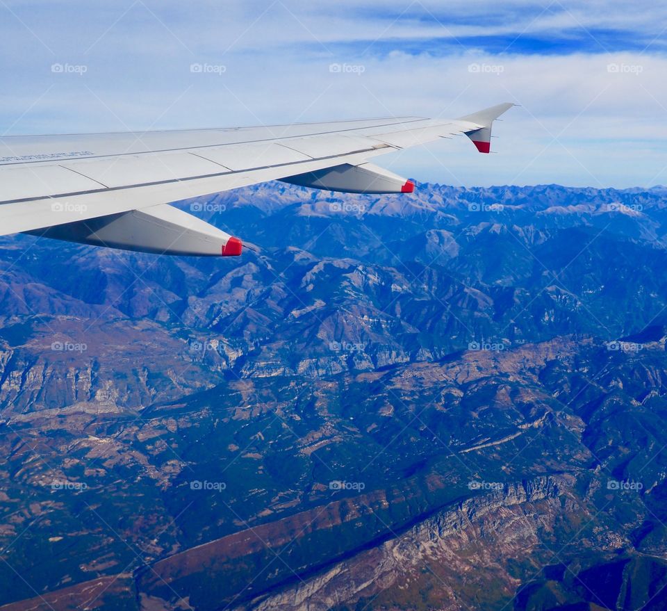 Aerial view of French Alps from behind wing of plane after takeoff from Nice, France.