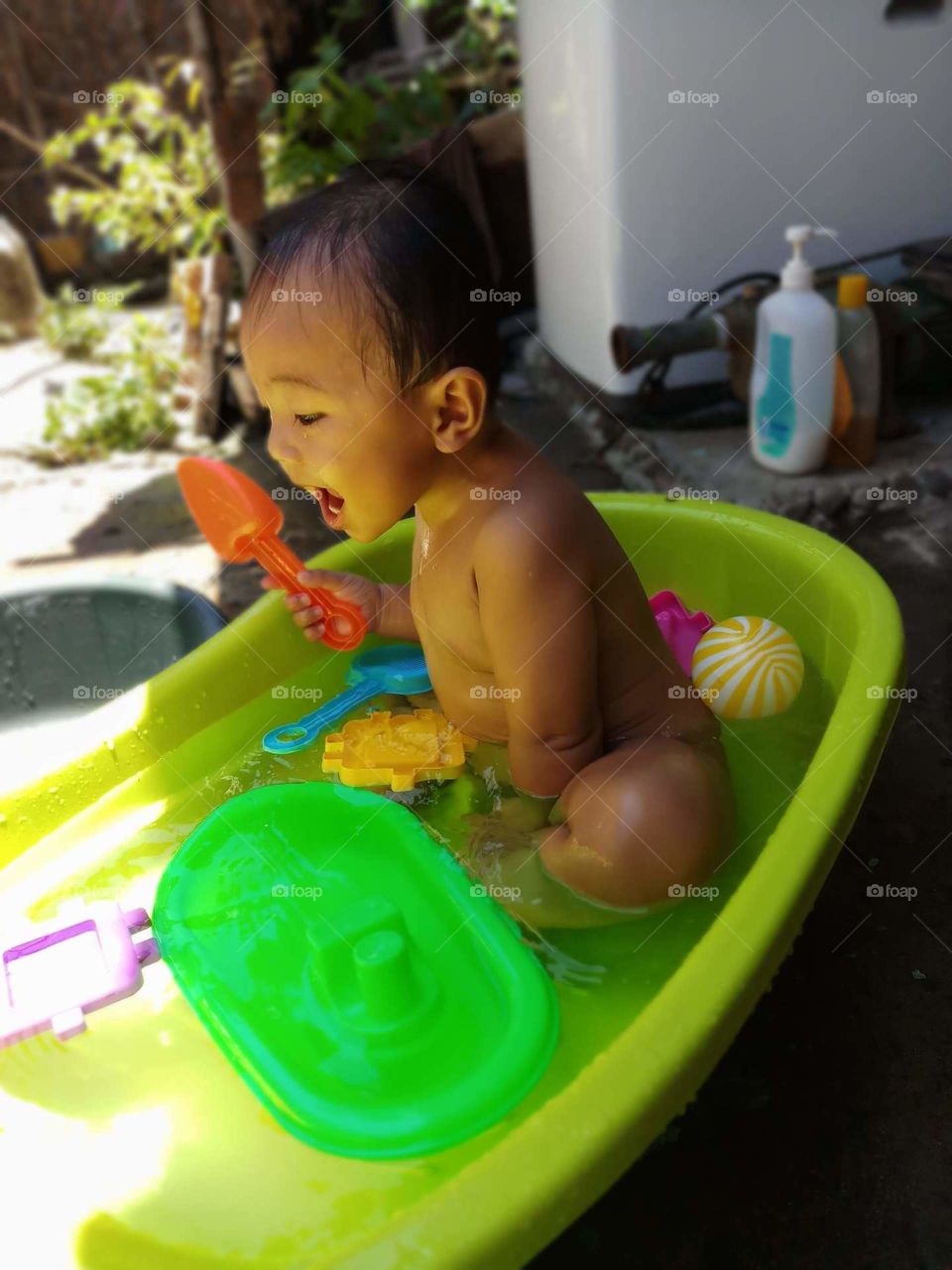 little boy enjoying while taking a bath with his toys.