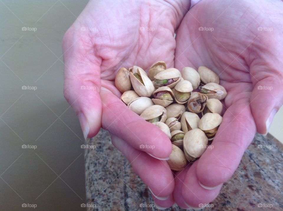 Holding a handful of pistachio nuts.