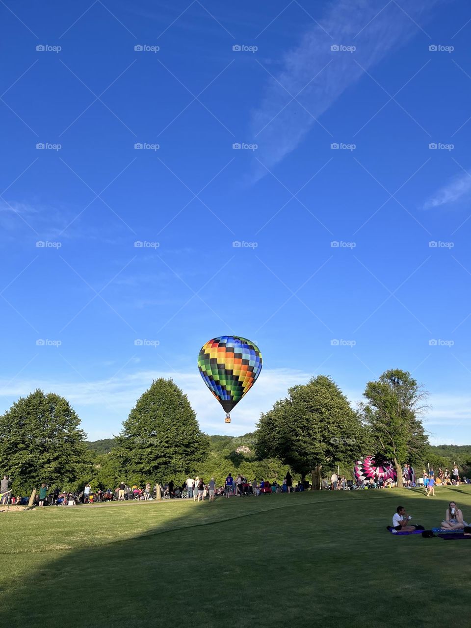 Colorful hot air balloon floating atop a grass field