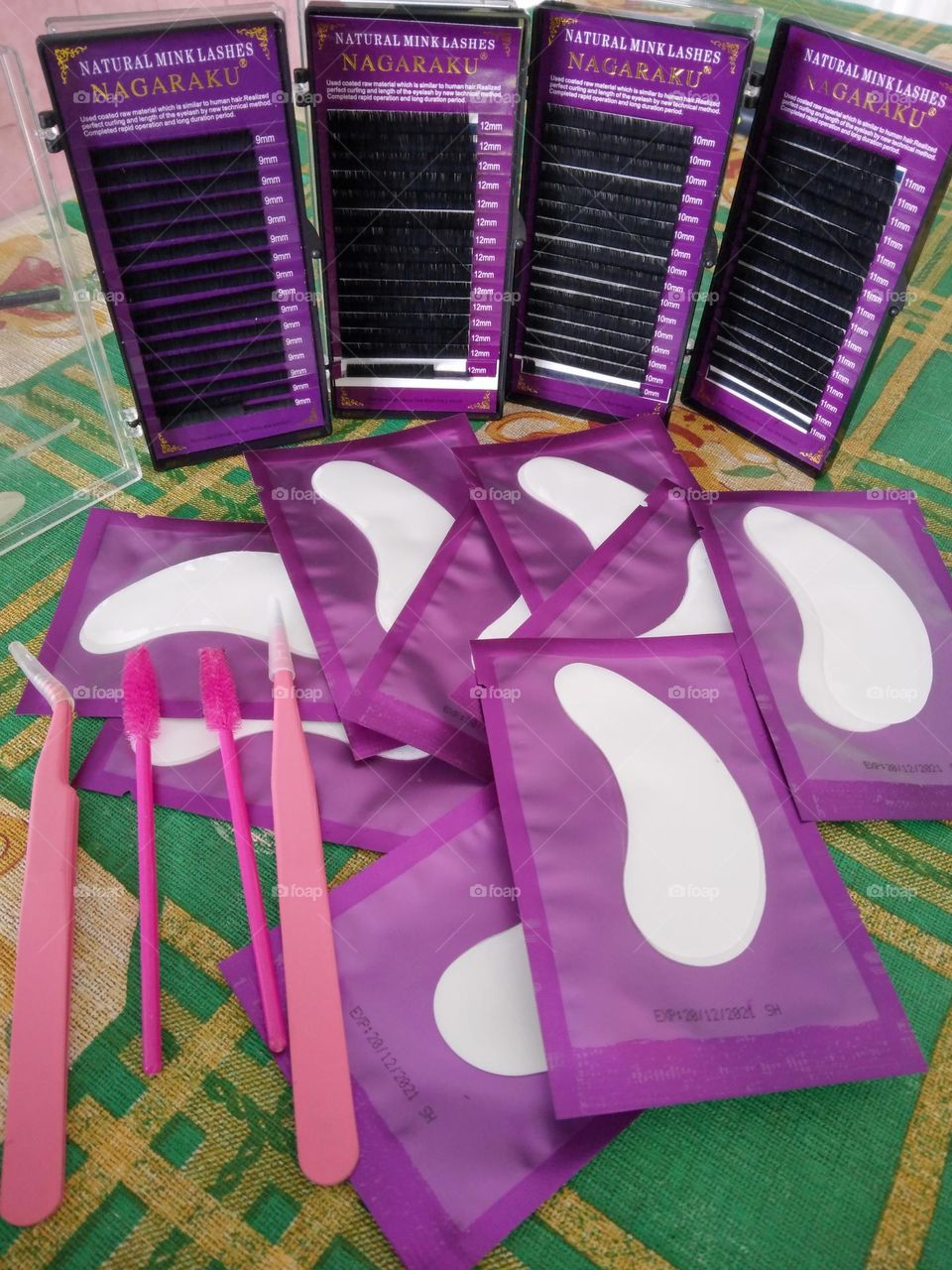 lashes, under eye pads, mascara brush, and pink tweezers