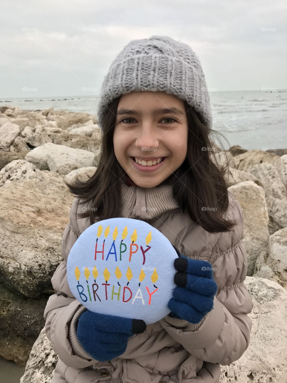 Girl holding pebble stone with birthday text at beach