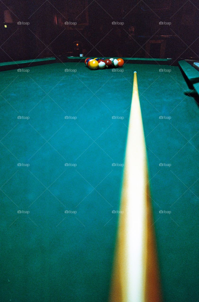 Isolated focus of racked billiard balls with cue stick in foreground 