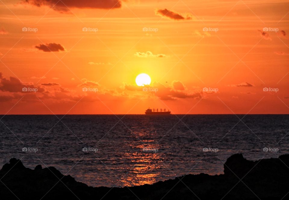 A hot, orange sunset over the horizon of the Mediterranean sea after a sweltering summer day. Location of photo is in Gozo.