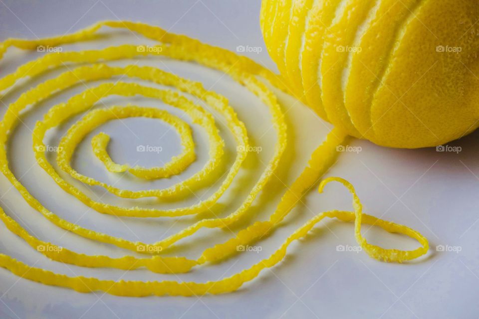 Closeup of a lemon and spiraled lemon peel on a white plate 