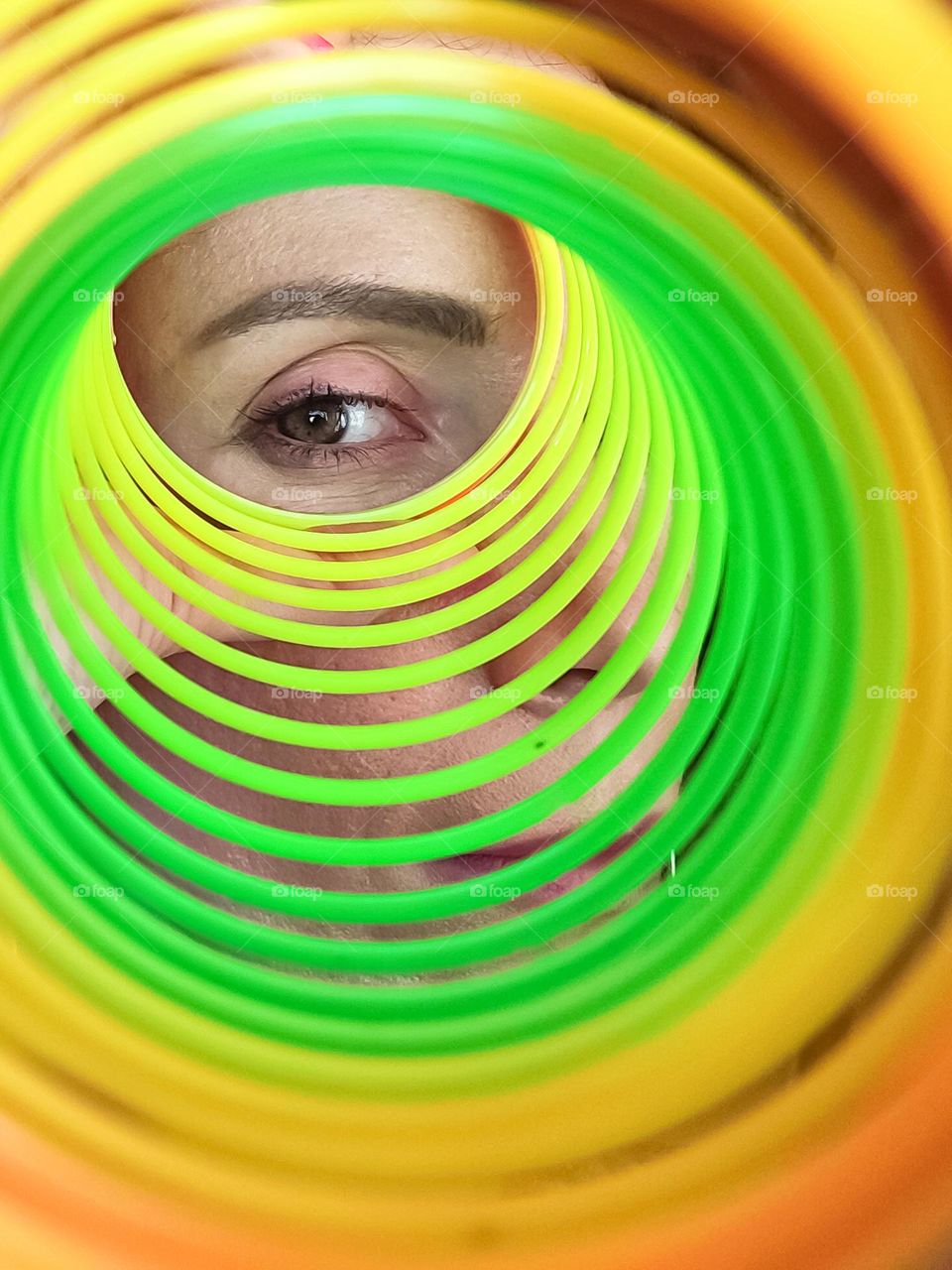 Circle, A Woman Looks through Rainbow Spring Toy