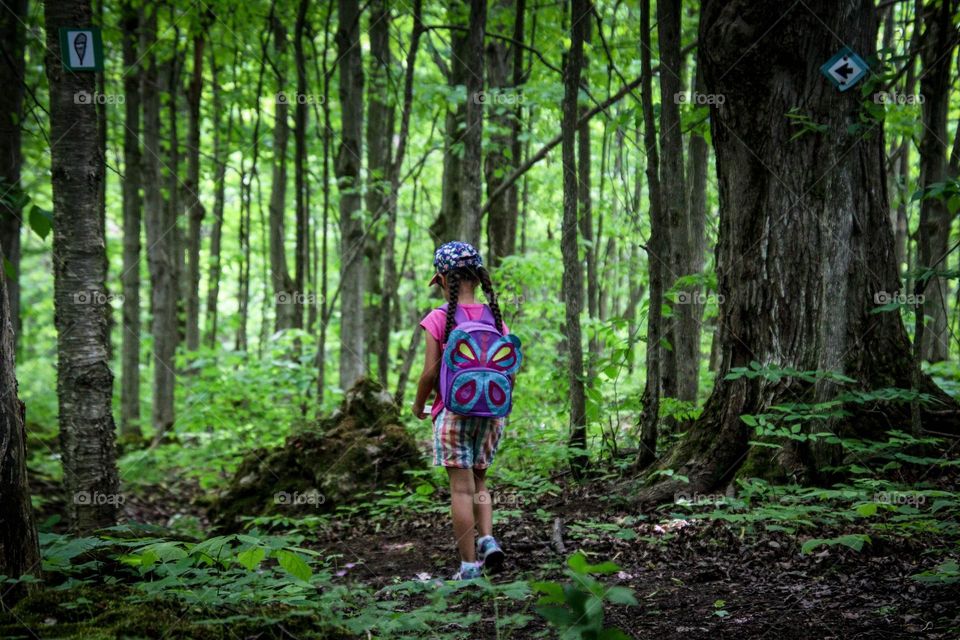 Little girl is hiking in a forest