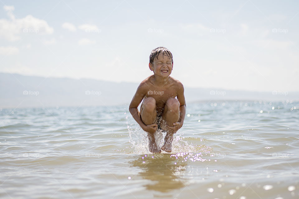 Boy jumping over water surface