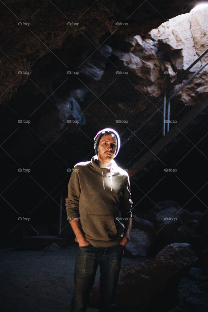 Man looking at camera in a cave with a light beam shining on his face
