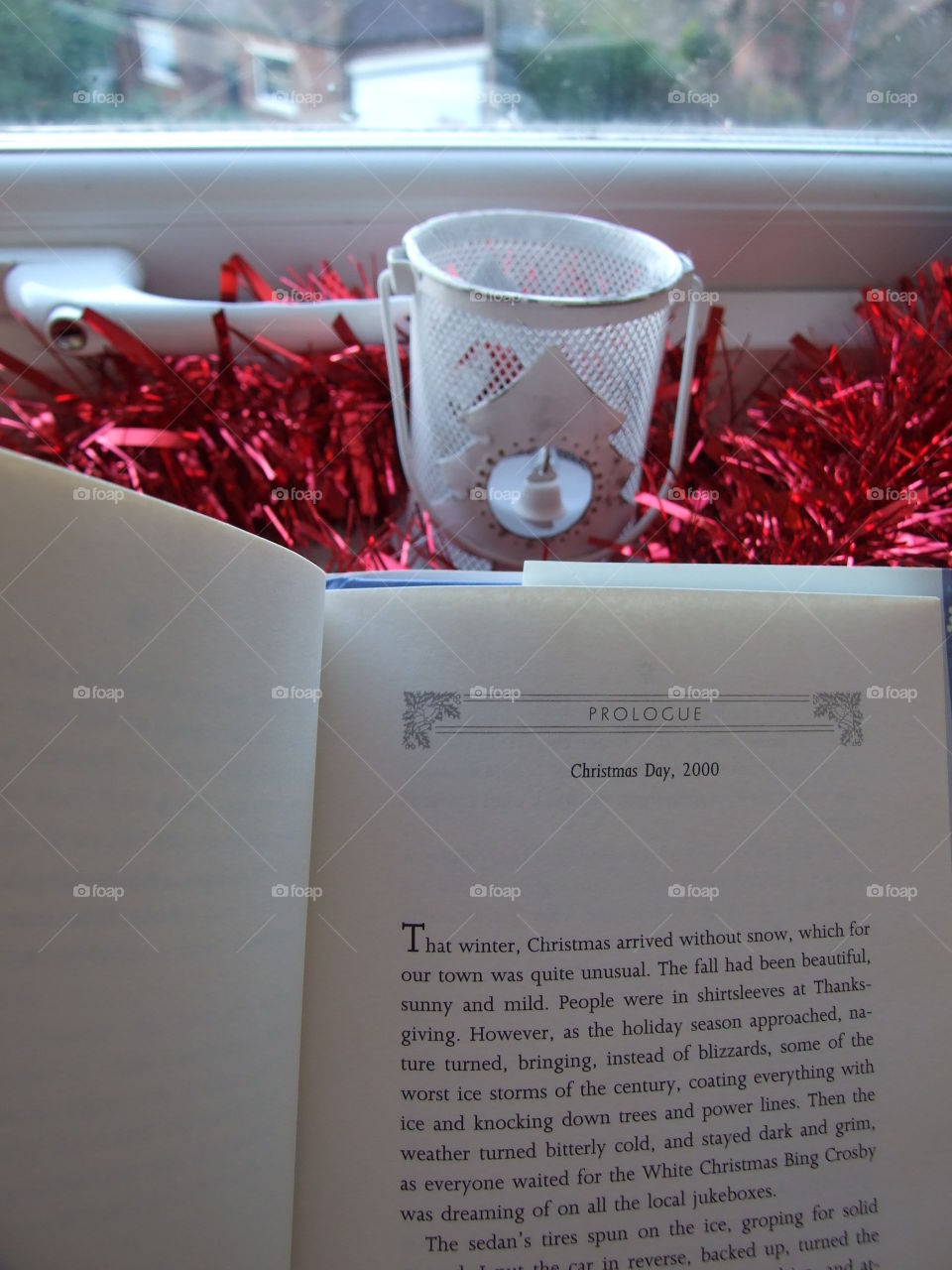 Reading a Christmas book with red tinsel and tealight holder in the background