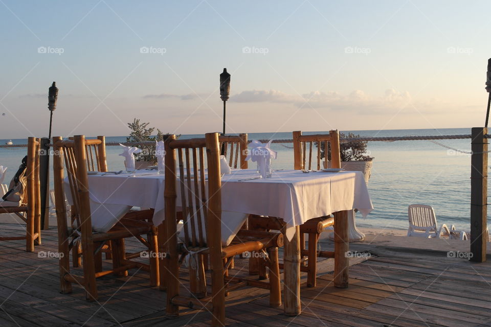 Wooden table and chairs set up in Sunset with a seaview 