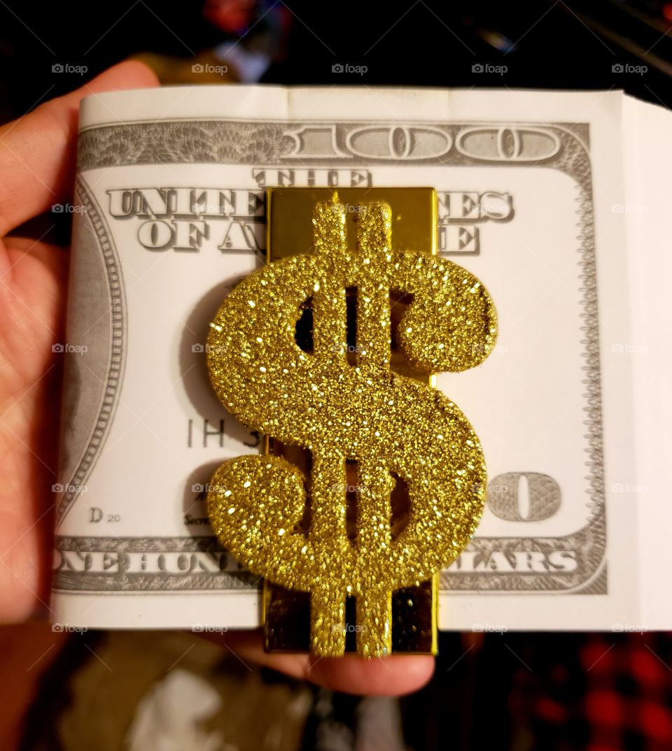 Gold sparkled dollar sign money clip holds a wad of money