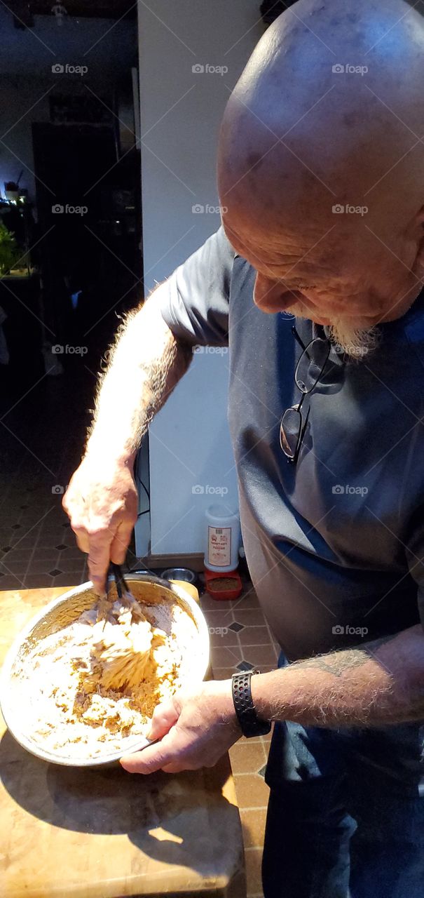 Man stirring & wisking muffin batter for made from scratch sweet potato muffins. Ready to pour into muffin pans.