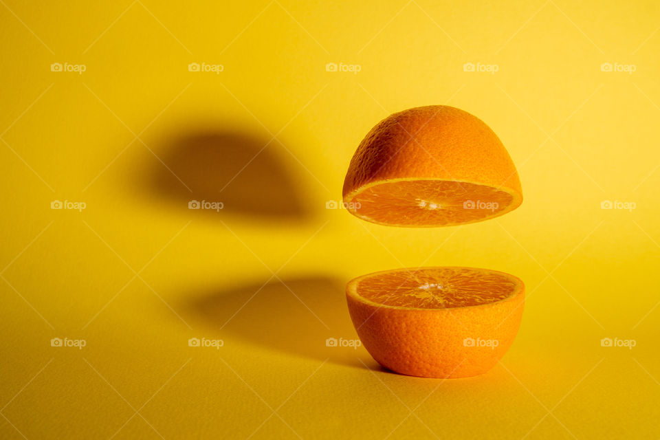 Fresh orange fruit sliced in half with one half floating