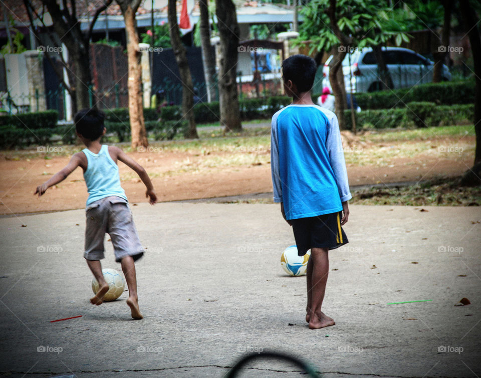 Indonesian child playing football with no football shoes. it's a common thing in Indonesia, playing football without shoes