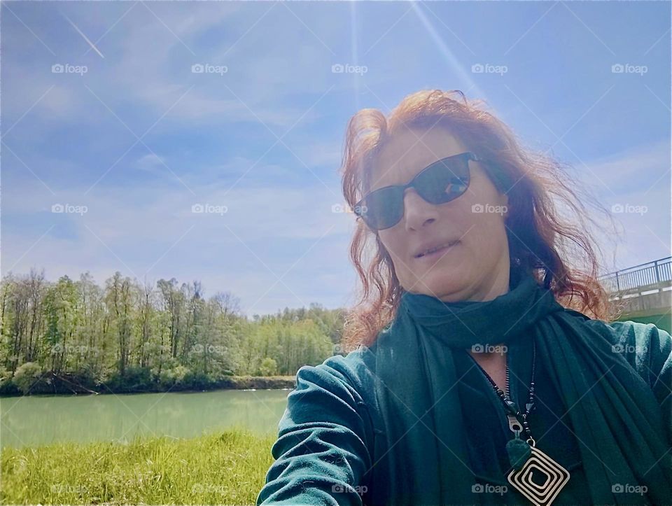 The young lady is standing at the shore of one of the lakes by „Bayerischzell“, a small but popular township near the Alps in „Bavaria“, Germany. The bright sunlight descends in the form of two visible rays over her head. 2024. Hypnotic Productions