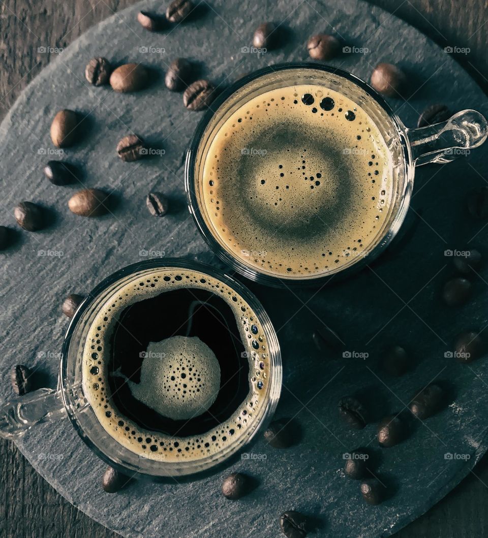 Two round coffee glasses, viewed from above showing tiny round bubbles on the frothy surface 