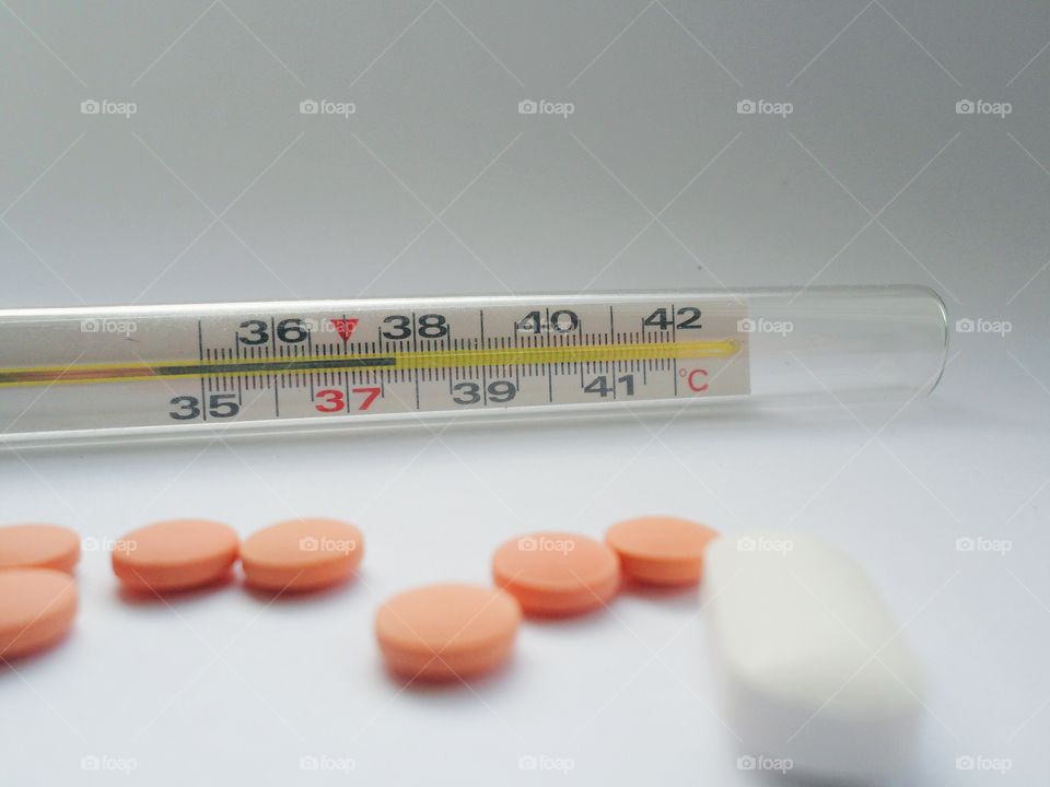 a thermometer for measuring temperature, tablets and pills on a white background