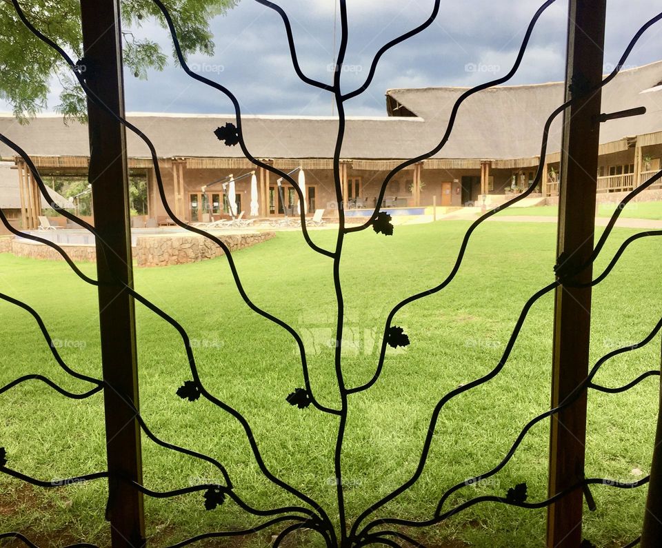 Nature metallic window bars with iron leaves. From the inside looking out to the brewing storm